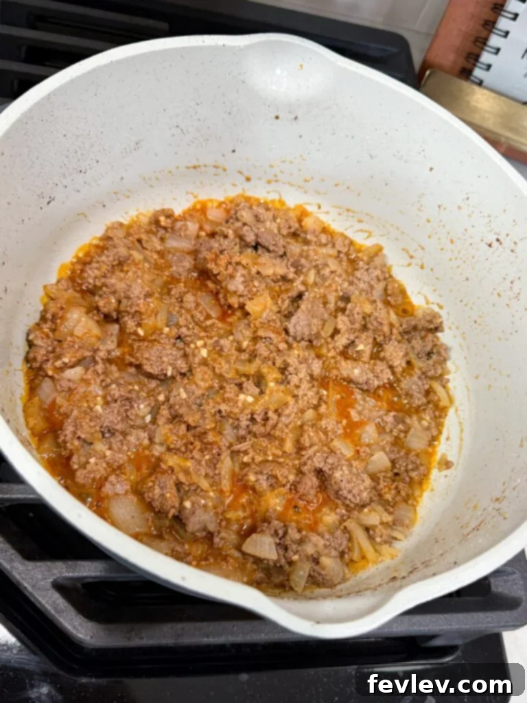 Easy Ground Turkey Hacks 22 Beautifully browned ground meat and sautéed onions, seasoned to perfection, simmering in a large skillet on the stovetop, illustrating the flavorful foundation of an easy recipe.