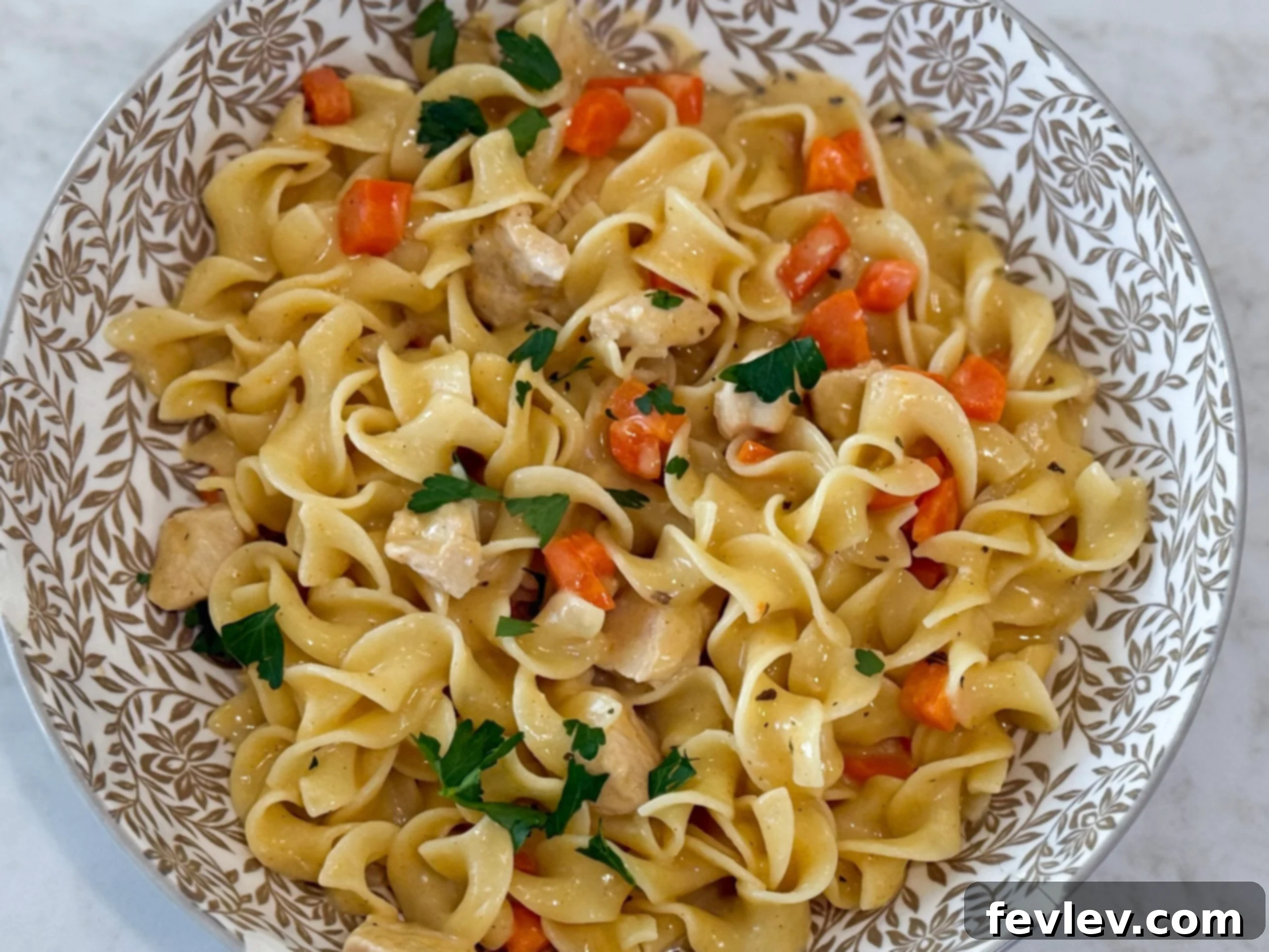 A steaming bowl of Creamy Chicken and Egg Noodles, garnished with fresh parsley, ready to be enjoyed.