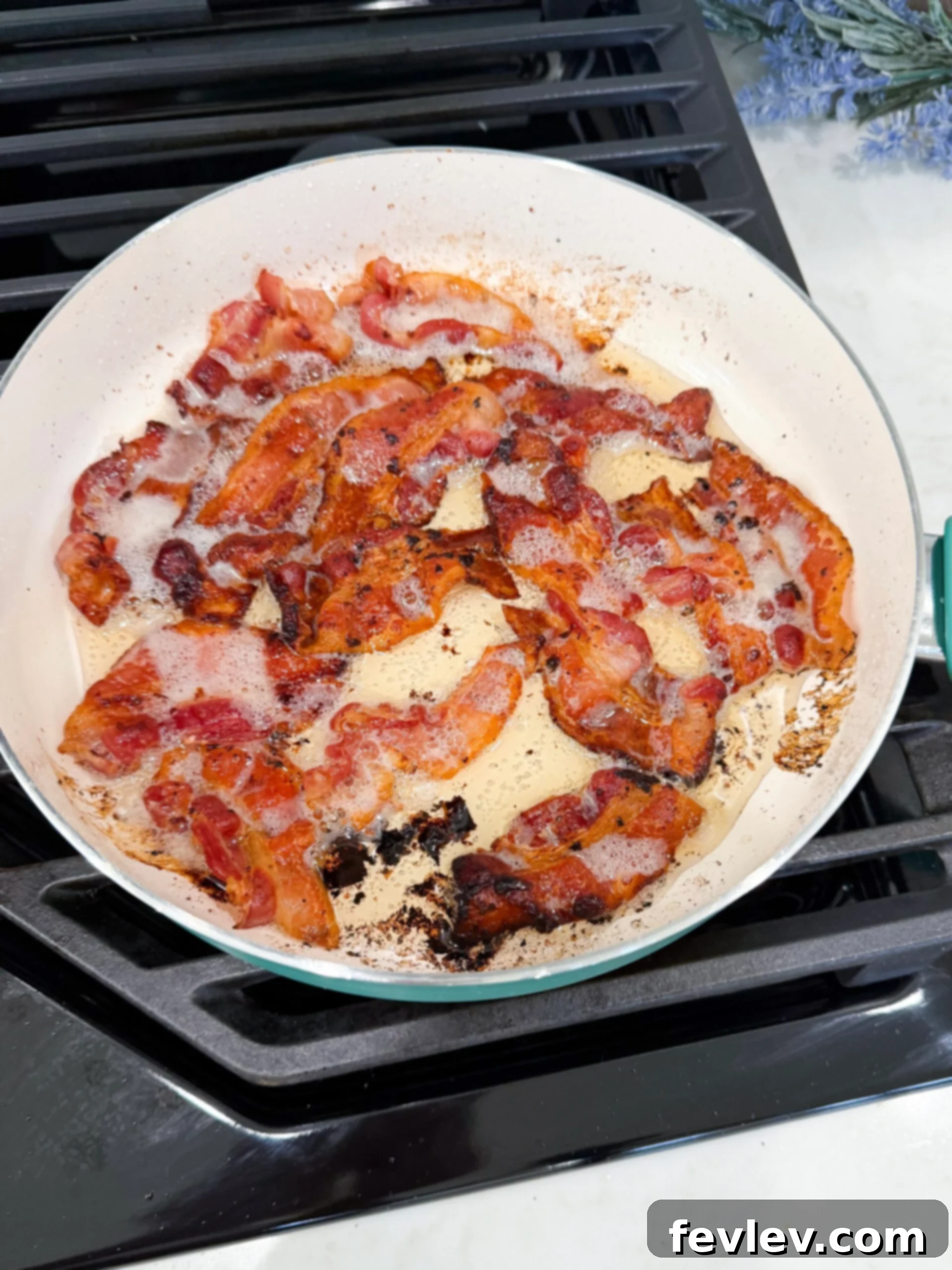 Creamy Tuscan Sausage Potato Kale Casserole 5 Crispy bacon pieces in hot grease in a pan.