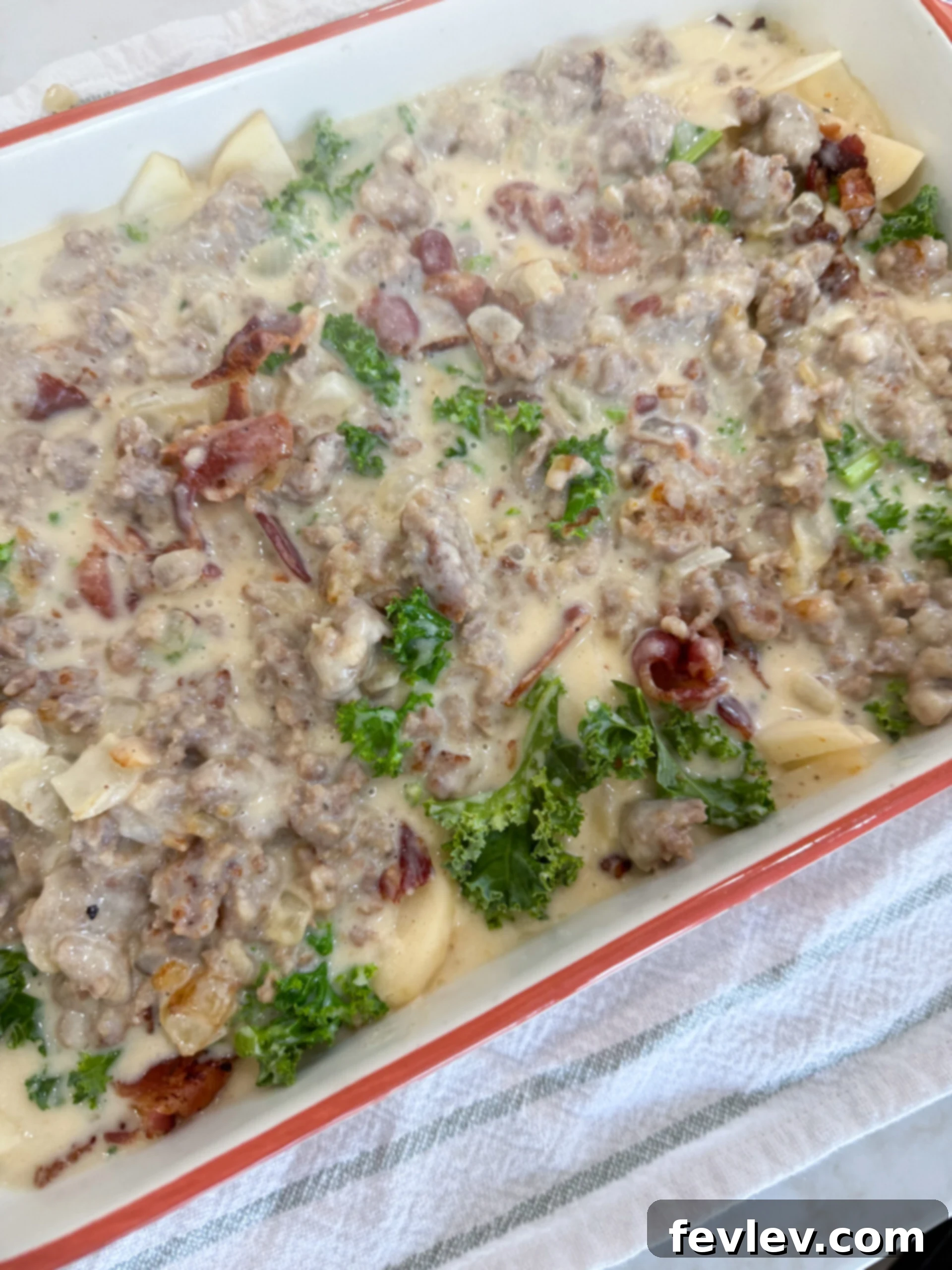 Creamy Tuscan Sausage Potato Kale Casserole 9 Casserole layered with sausage cream sauce and sprinkled with Parmesan cheese before baking.