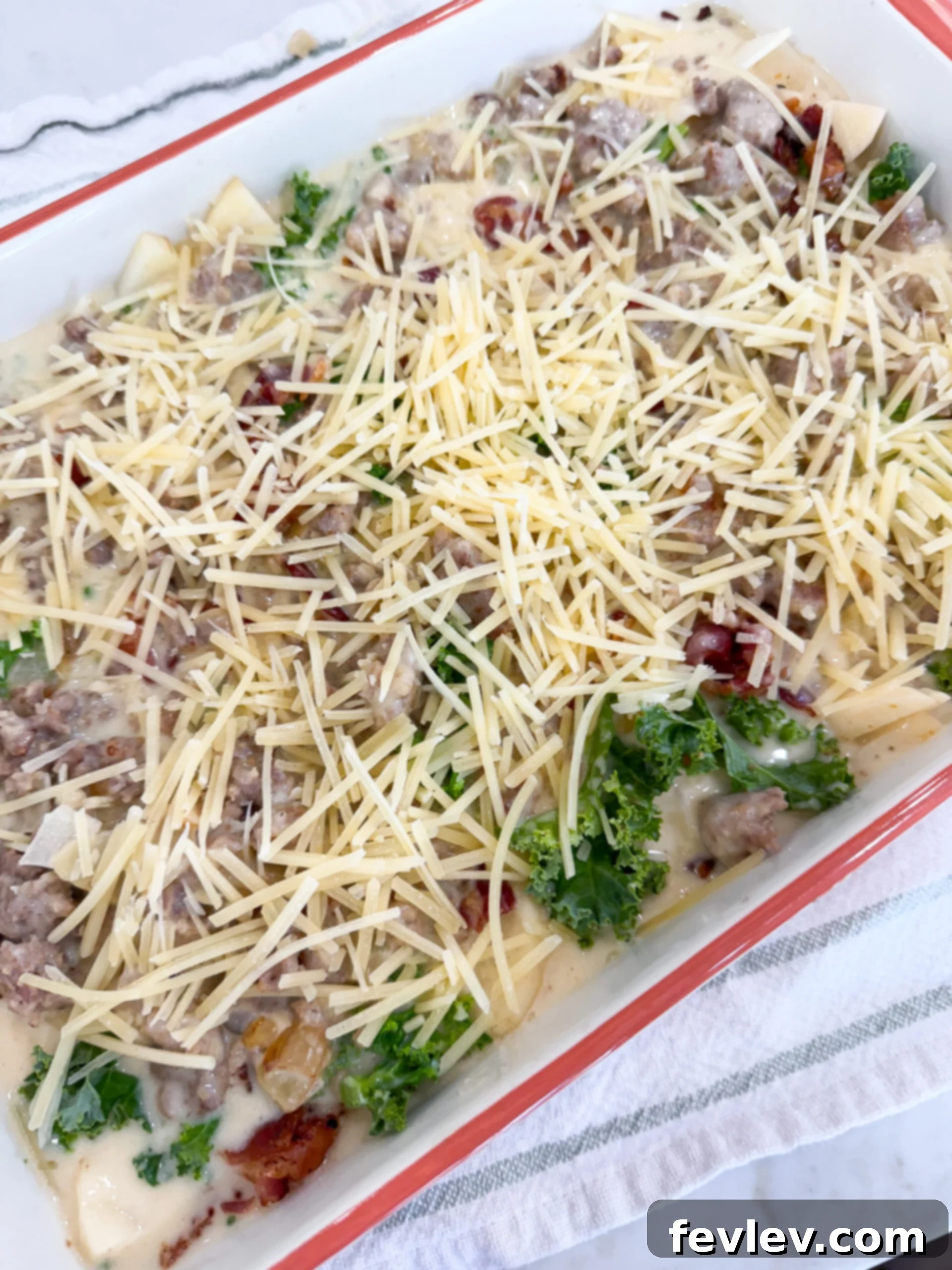 Creamy Tuscan Sausage Potato Kale Casserole 10 Toscana Casserole layered with sausage cream sauce and sprinkled with Parmesan cheese before baking.