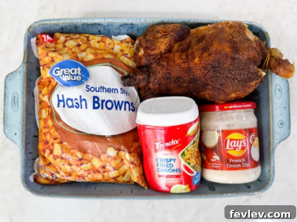 All the essential ingredients for French Onion Chicken Potato Casserole laid out: shredded chicken, frozen hash browns, cheddar cheese, French onion dip, cream of mushroom soup, and a container of French fried onions.