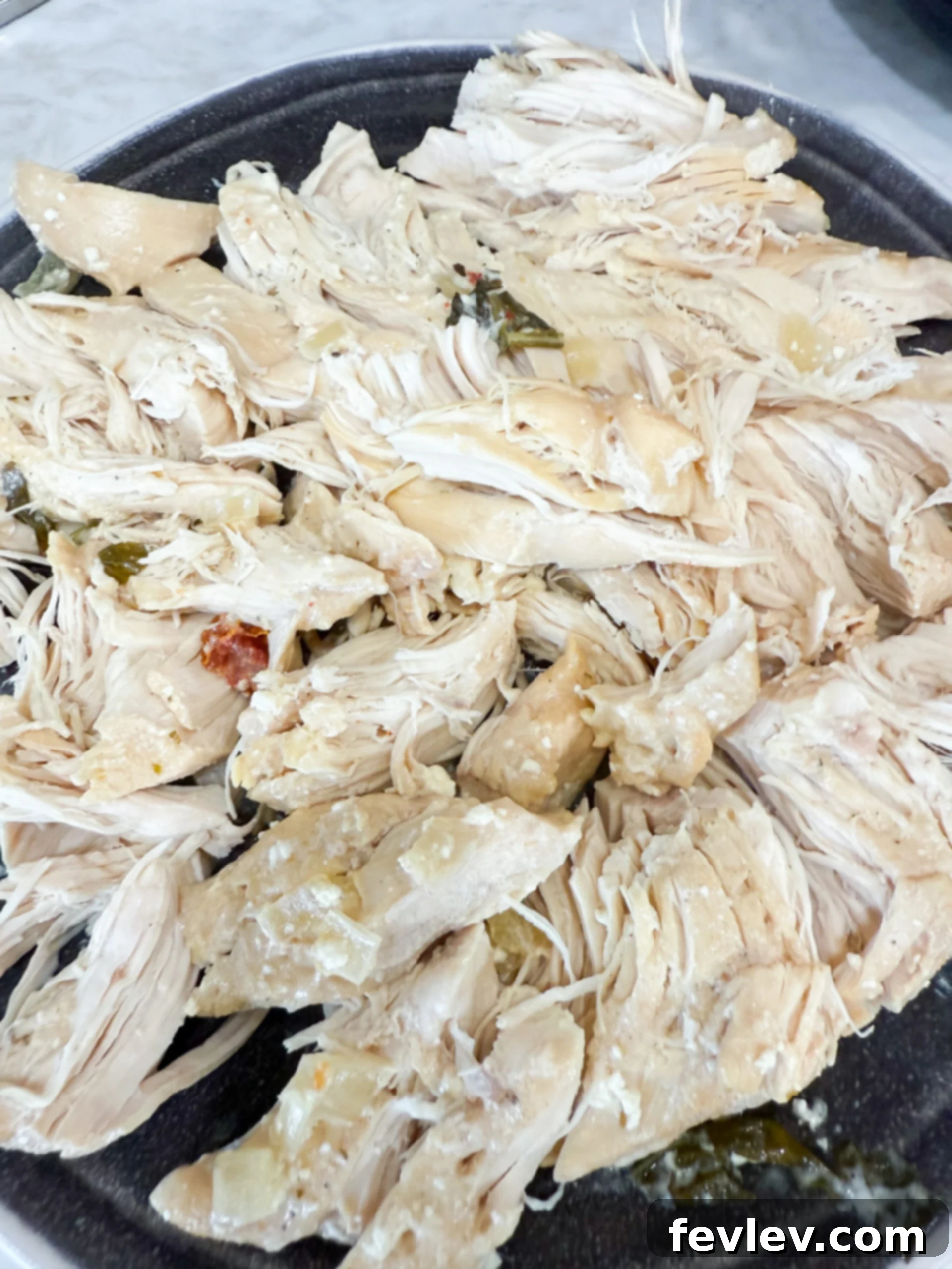 Irresistible Slow Cooker Marry Me Chicken Soup 6 Shredded cooked chicken on a cutting board, ready to be returned to the slow cooker soup.