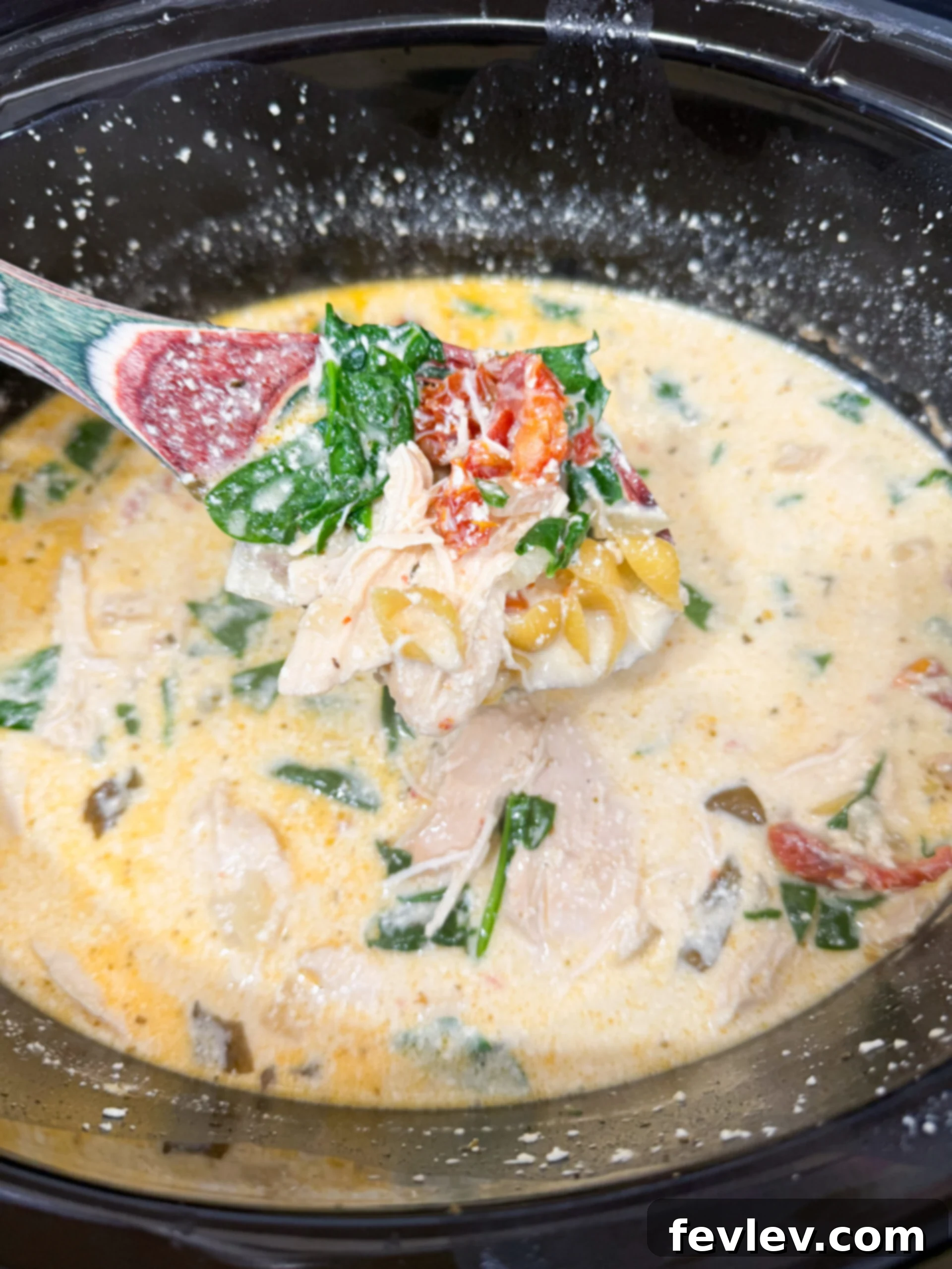 Irresistible Slow Cooker Marry Me Chicken Soup 7 Small pasta shells and fresh spinach being stirred into the creamy chicken soup in the slow cooker.