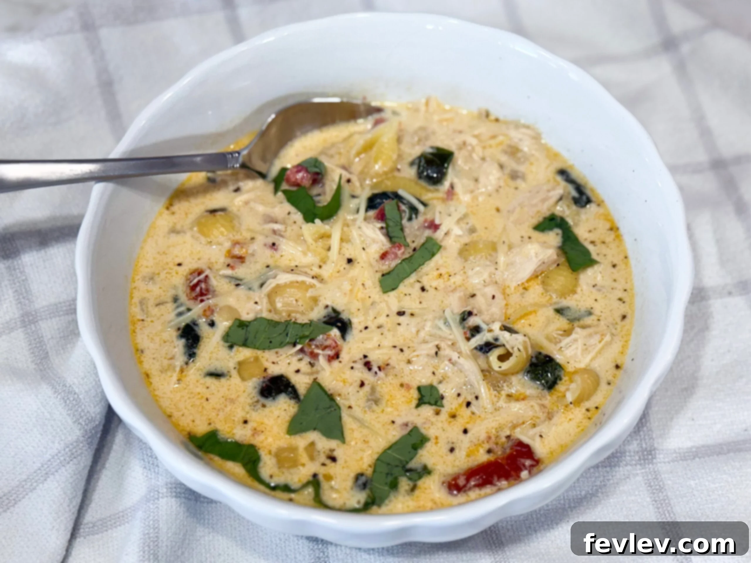 Irresistible Slow Cooker Marry Me Chicken Soup 9 A large white bowl filled with creamy Slow Cooker Marry Me Chicken Soup, showcasing tender chicken, pasta, and vibrant green spinach, ready for a family dinner.