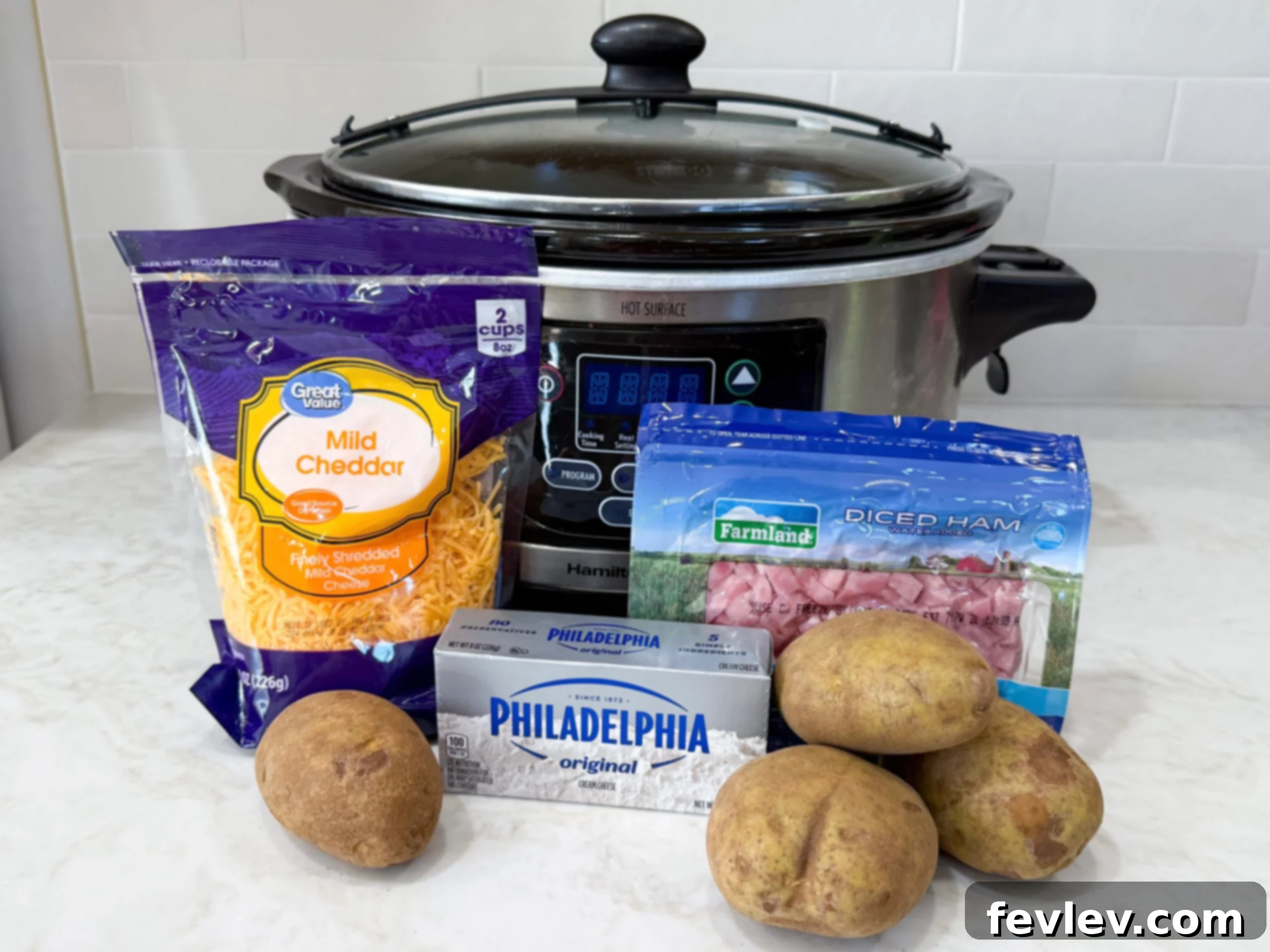 Variety of fresh ingredients for Slow Cooker Ham and Potato Soup, including diced ham, russet potatoes, carrots, celery, onion, and spices, neatly arranged on a kitchen countertop