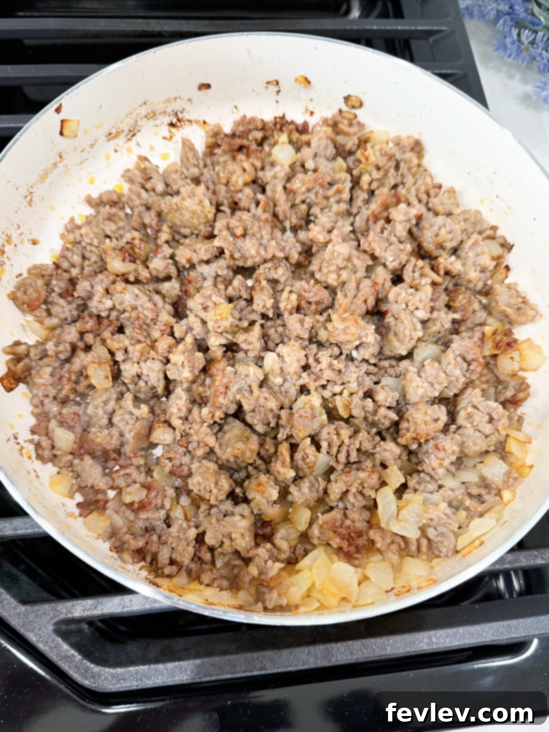 Tuscan Slow Cooker Sausage and Vegetable Soup 4 Close-up of crumbled Italian sausage and diced yellow onion browning and caramelizing in a hot skillet, showcasing the development of rich, savory flavors before being transferred to the slow cooker.