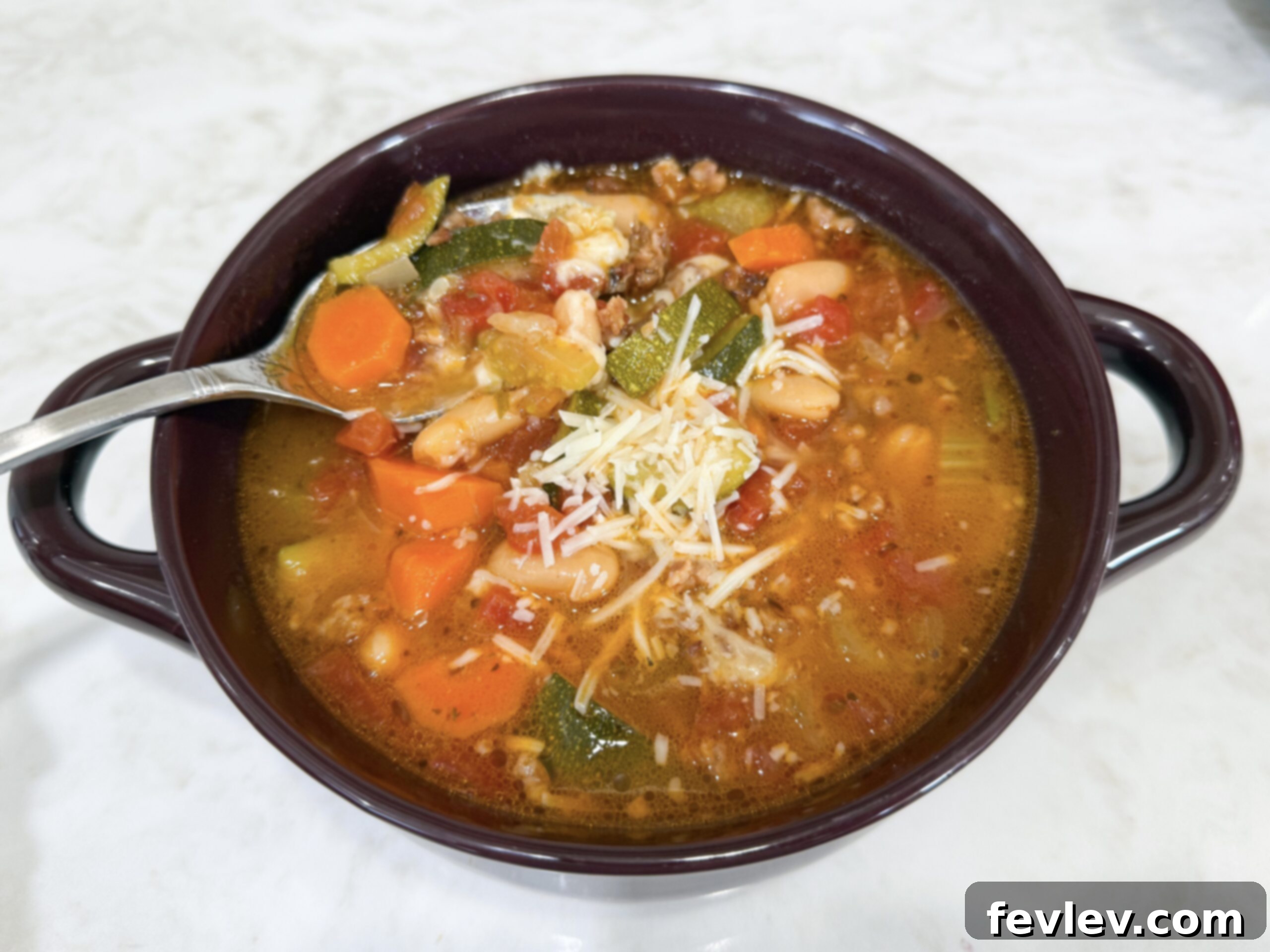 Tuscan Slow Cooker Sausage and Vegetable Soup 8 A perfectly portioned bowl of Slow Cooker Italian Vegetable and Sausage Soup, garnished with a generous topping of freshly grated Parmesan cheese and a sprig of fresh basil, ready to be served and enjoyed as a comforting meal.