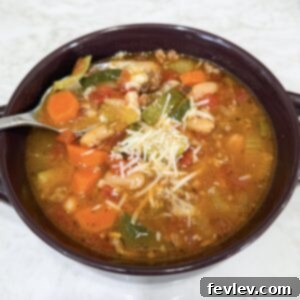 A vibrant bowl of Slow Cooker Italian Vegetable and Sausage Soup, garnished with fresh Parmesan cheese and herbs, presented as a comforting and easy meal solution.