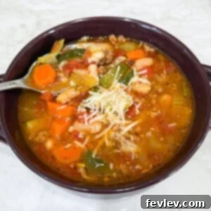 A beautiful bowl of Italian Vegetable and Sausage Soup, generously topped with freshly grated Parmesan cheese and a sprinkle of herbs.