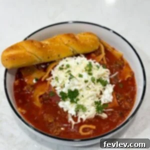 A bowl of Slow Cooker Lasagna Soup, served with a spoon and garnished with fresh herbs, showcasing its rich and inviting appearance.