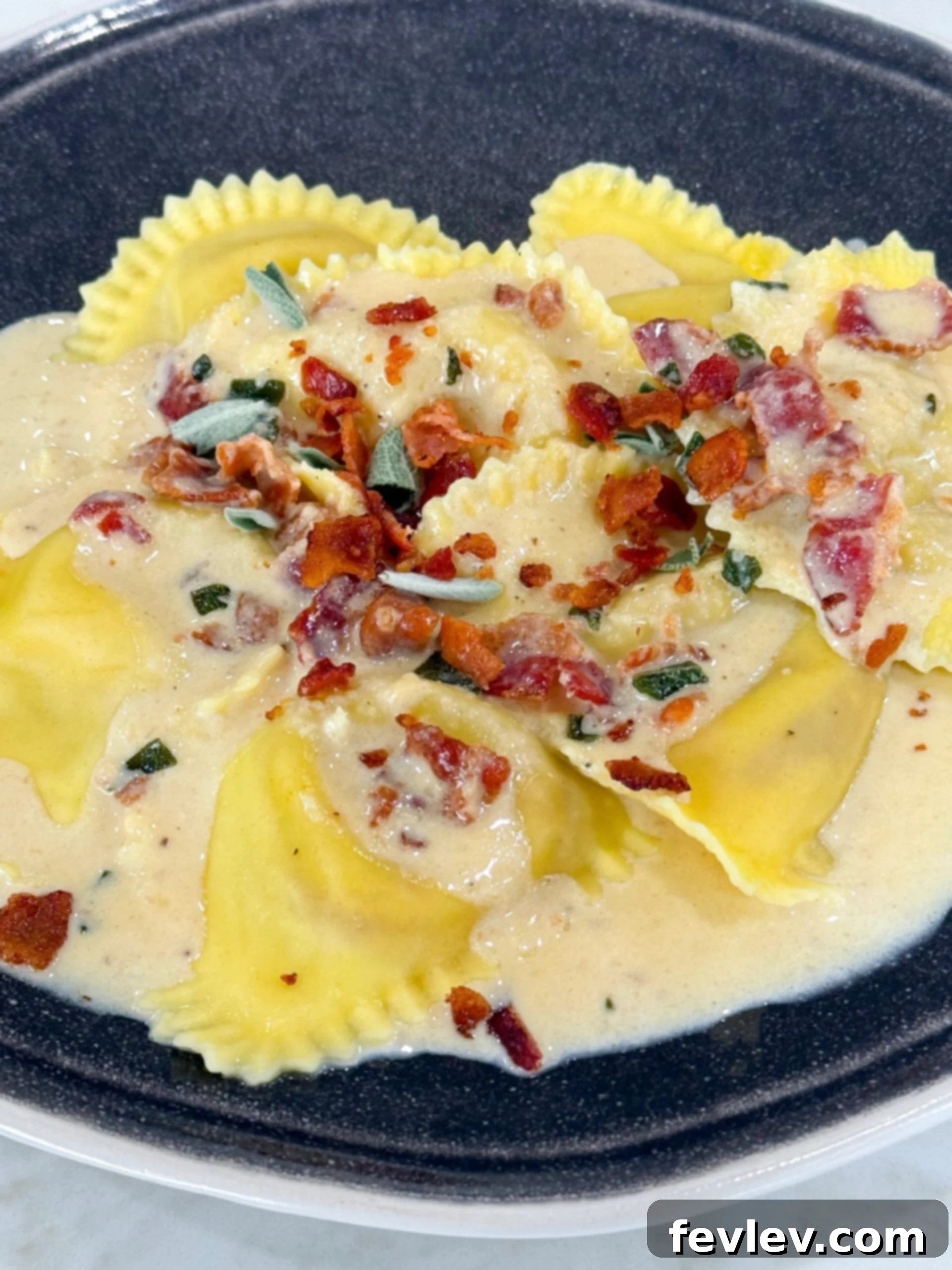 Butternut squash ravioli generously coated in a creamy maple bacon sage sauce, presented beautifully in a dish.