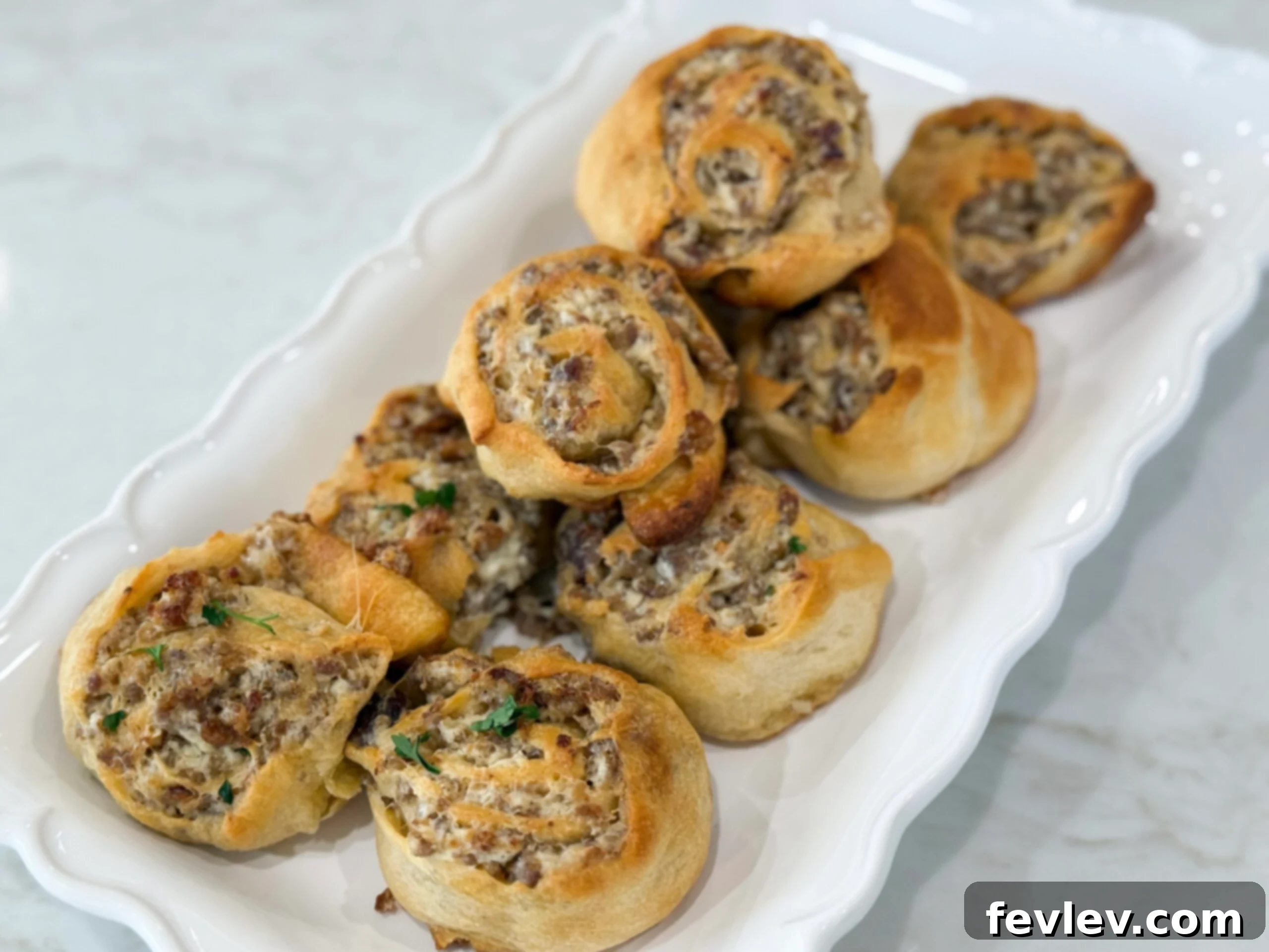 Golden brown sausage cream cheese pinwheels, freshly baked and arranged on a tray, showcasing their flaky texture and savory filling.