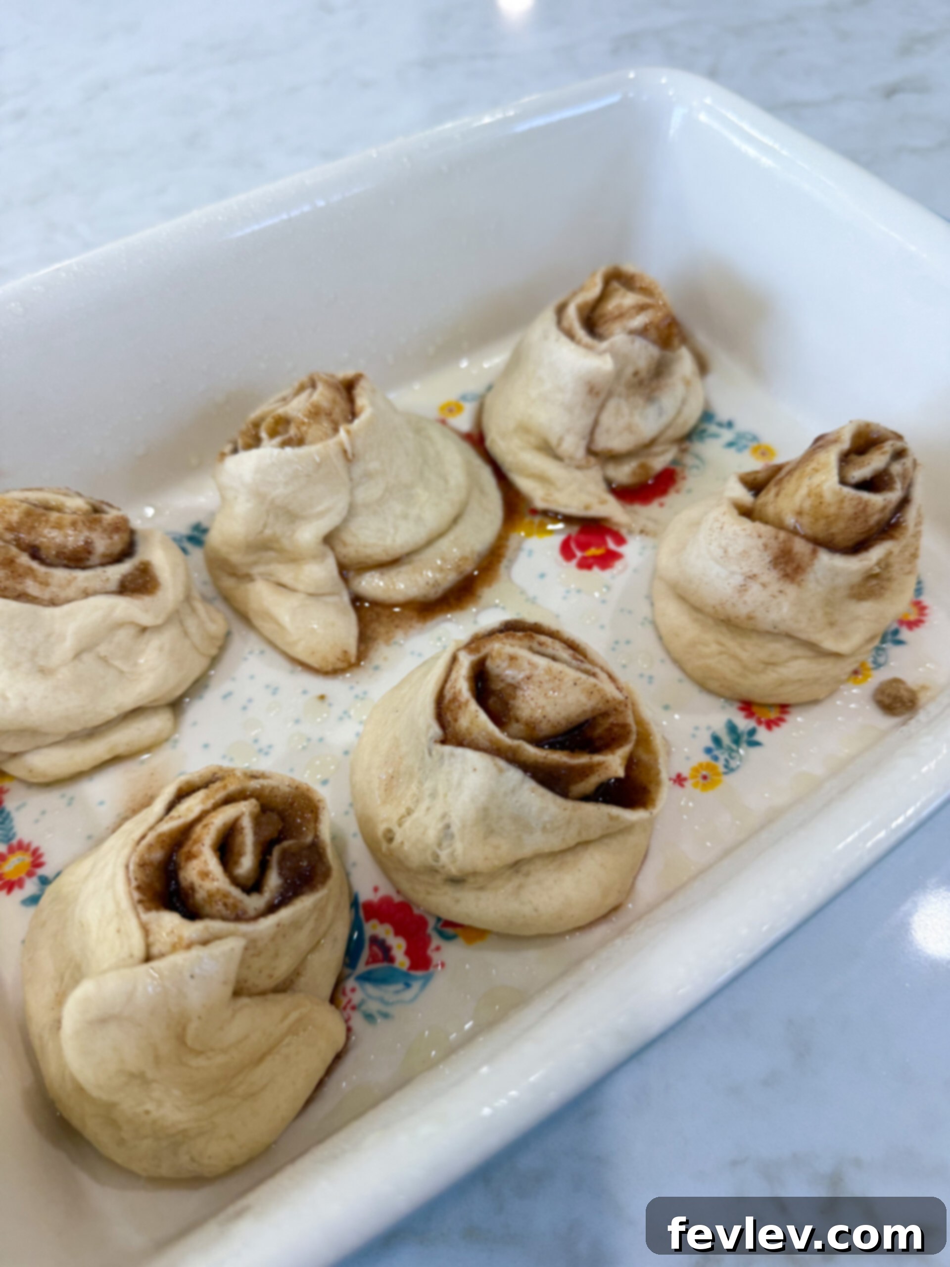 Six sliced crescent roll cinnamon rolls neatly arranged in a baking dish, ready for baking.
