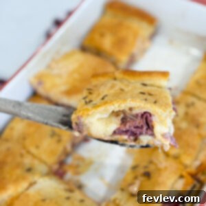 Close-up of a slice of Pastrami Crescent Sandwich Bake, showing layers of pastrami, Swiss cheese, and sauerkraut.