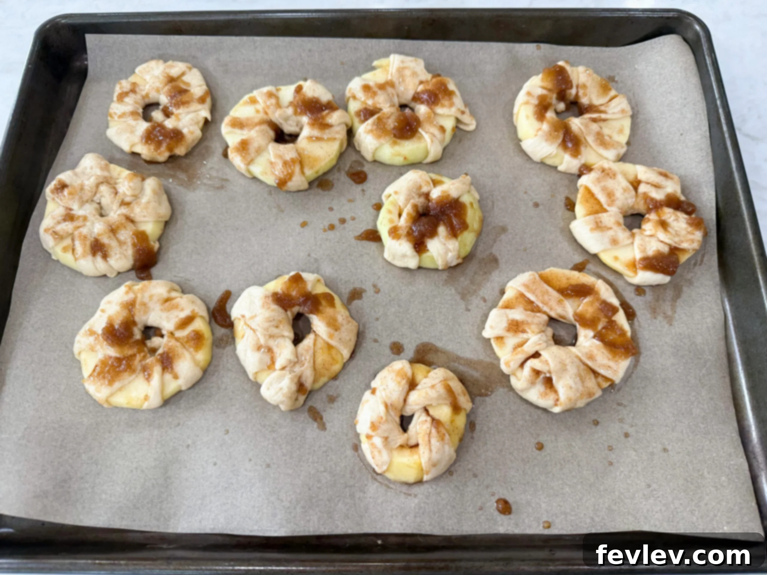 Brushing cinnamon sugar butter on wrapped apple donuts before baking