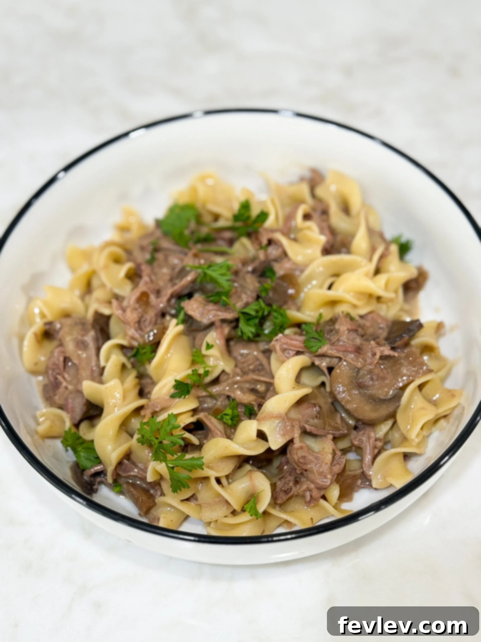 Tender & Creamy Slow Cooker Beef Stroganoff 2 Slow cooker beef stroganoff served with egg noodles and fresh parsley garnish
