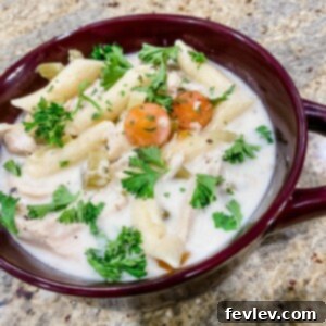 A steaming bowl of creamy chicken noodle soup, garnished with fresh herbs, perfect for a cozy meal.