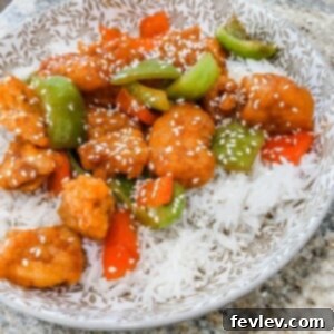 Crispy Sweet and Sour Chicken served with rice, garnished with bell peppers