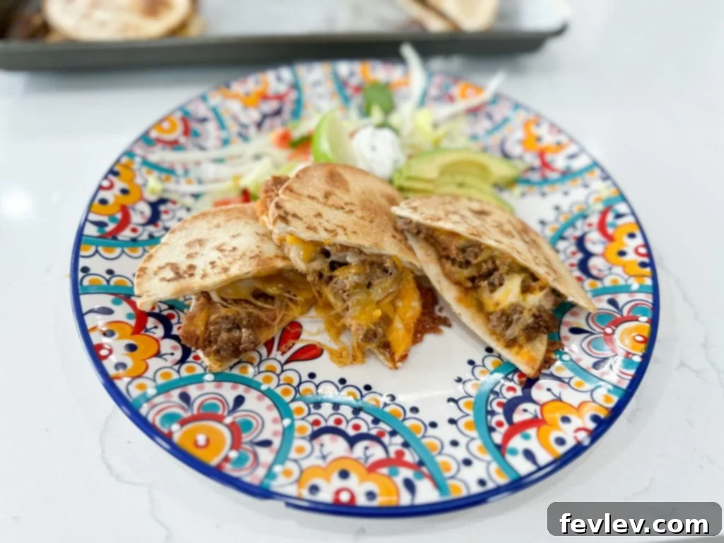 Six uncooked quesadillas neatly assembled on a parchment-lined sheet pan, ready to be placed in the oven for baking. The fillings are visible between the tortilla layers.