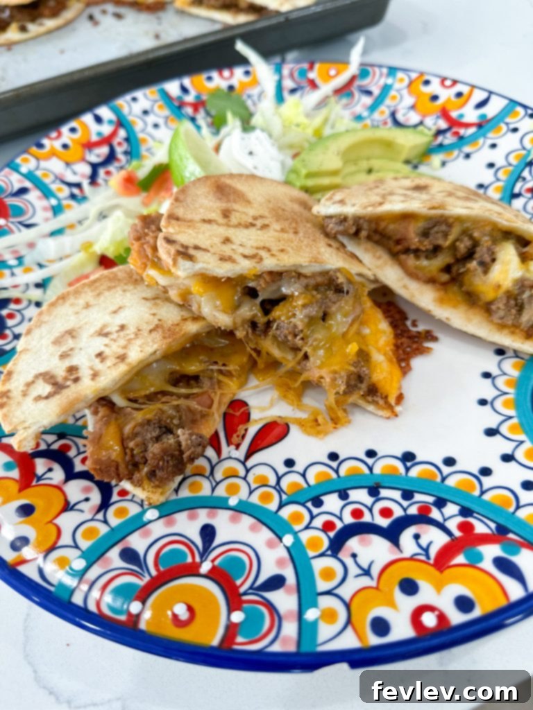 A close-up shot of a single baked quesadilla, sliced in half, showcasing its golden-brown, crispy tortilla exterior and the rich, melted cheese and beef filling inside.