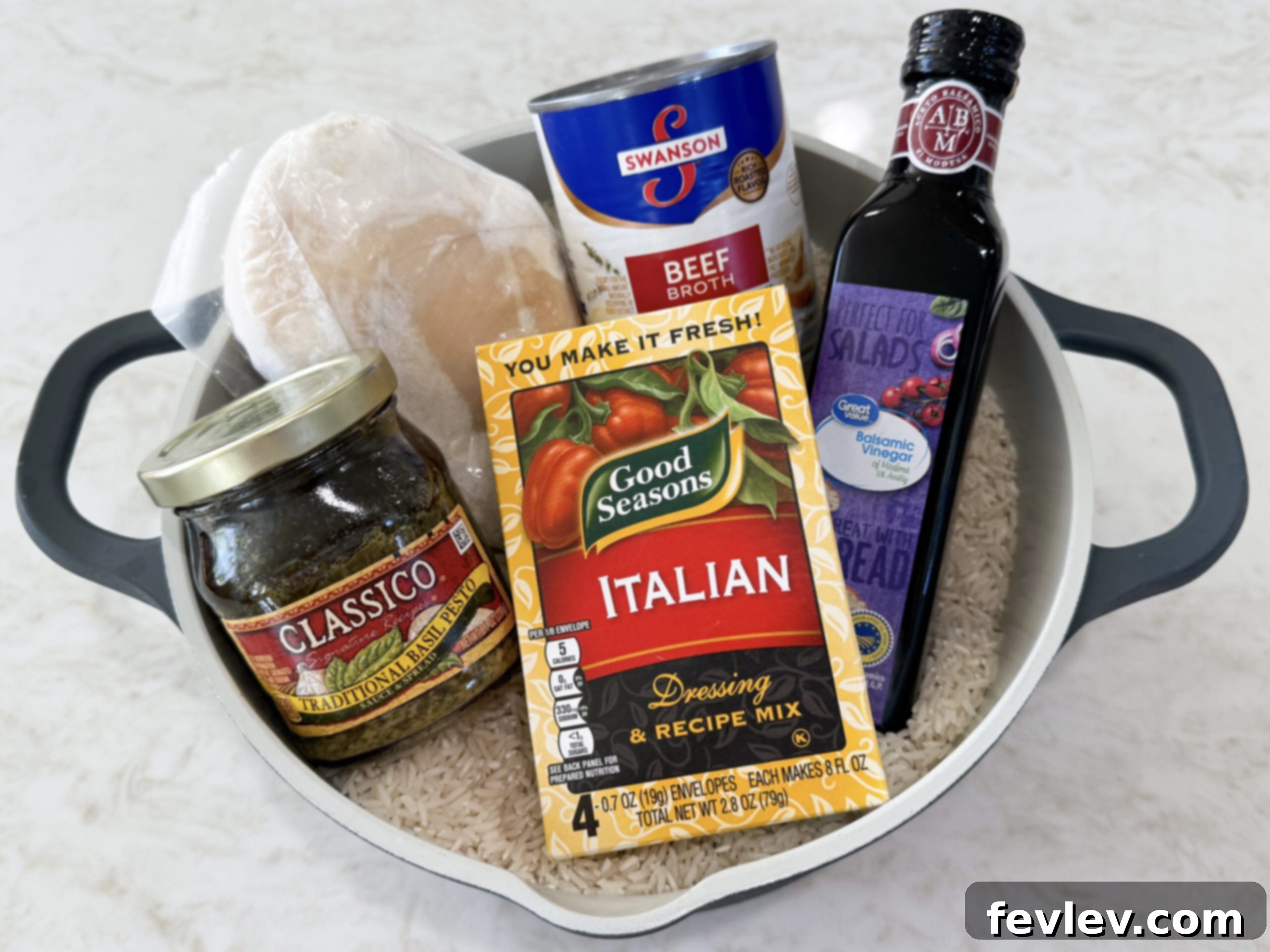 A vibrant collection of fresh, whole ingredients for Caprese Chicken and Rice, including plump chicken breast, bright red tomatoes, creamy mozzarella, aromatic basil leaves, and balsamic vinegar, arranged invitingly on a wooden surface.
