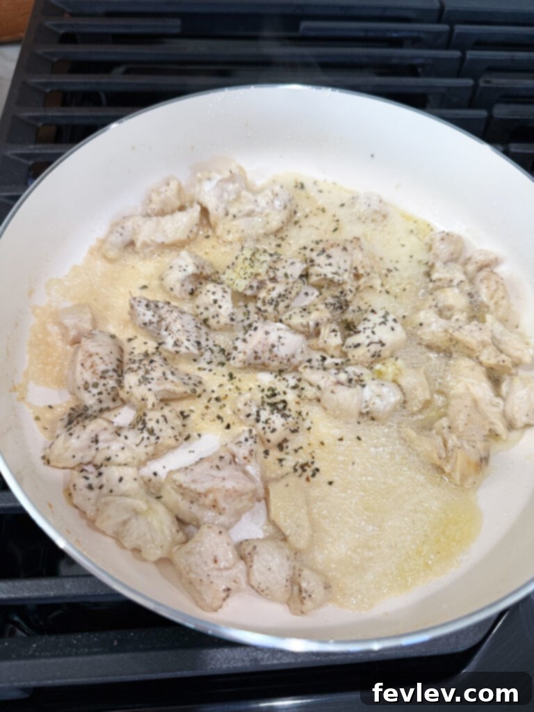 Minced garlic and dried basil being stirred in a hot skillet, releasing their aromatic scents and creating a fragrant base for the Caprese Chicken and Rice.