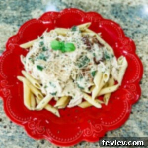 A rich and creamy Tuscan Alfredo Chicken dish with tender chicken, sun-dried tomatoes, and fresh spinach served over penne pasta.