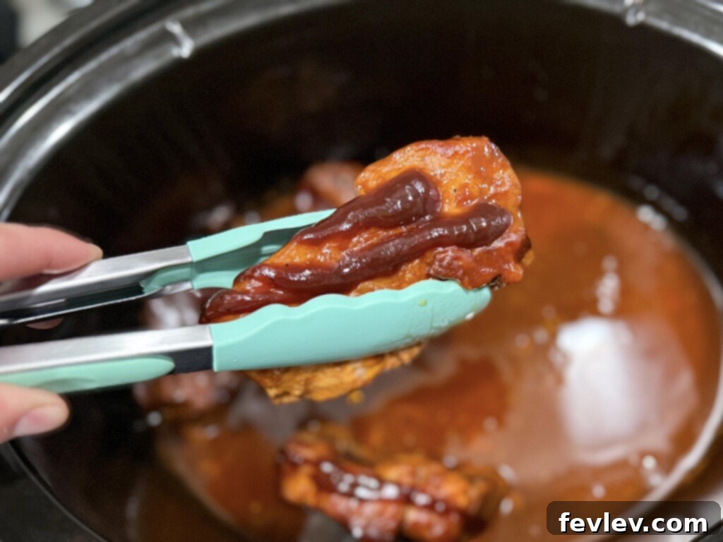 Prime Pork Rib Cut 4 Tender slow cooked boneless pork ribs being brushed with extra BBQ sauce on a baking sheet before broiling