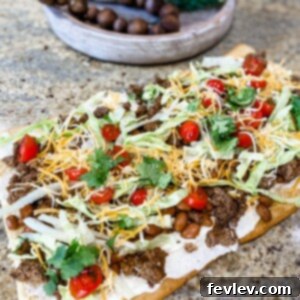 Ultimate Taco Pizza 2 Delicious Taco Pizza with seasoned beef, melted cheese, fresh lettuce, and tomatoes on a crispy crescent roll crust
