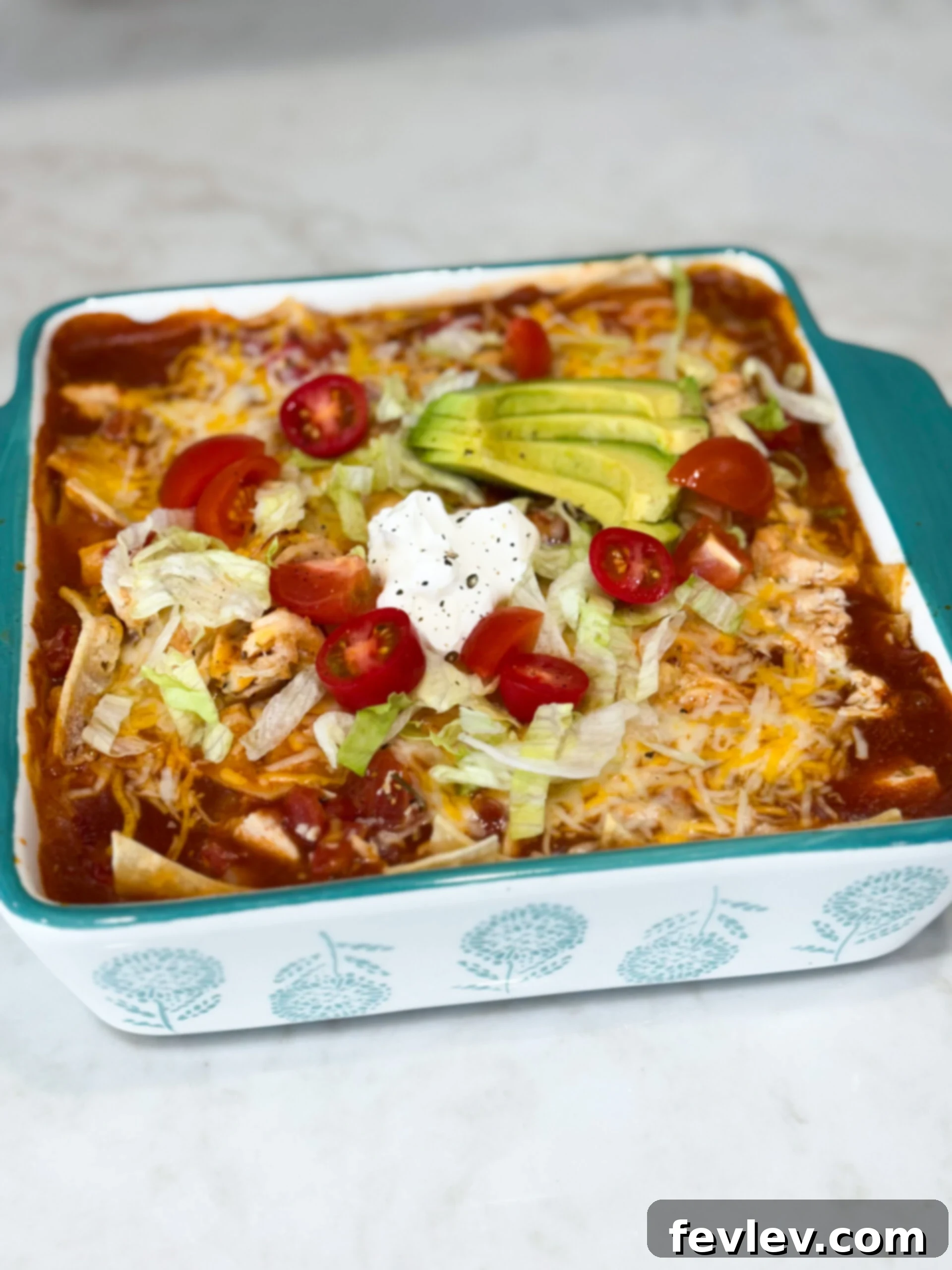 Red Chili Chicken Enchiladas 9 Pan of cheesy red chili chicken enchiladas topped with lettuce, tomatoes, sour cream, and avacado