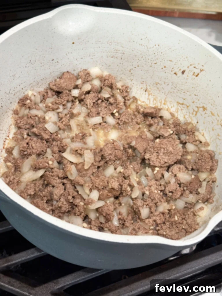 Beef Stroganoff 6 Ground beef and chopped onions browning together in a large skillet on the stovetop, forming the flavorful base of the stroganoff.