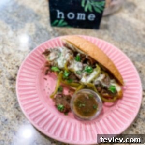 Close-up of a delicious Slow Cooker Philly Cheese Steak Sandwich with melted provolone cheese, tender beef, and sautéed peppers.