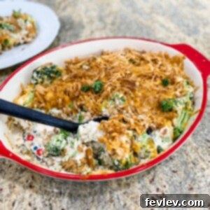 Delicious and creamy Cheesy Cheddar Broccoli Bake, garnished with crispy fried onions, in a round baking dish.