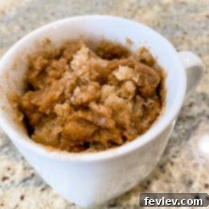 A delightful single-serving Microwave Cinnamon Coffee Cake in a mug, topped with crumble, ready to be enjoyed.