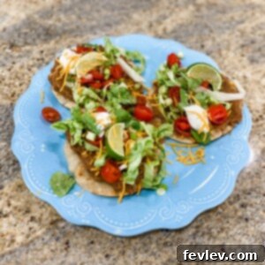 Crispy Tostadas piled high with refried beans, lettuce, tomatoes, cheese, and sour cream