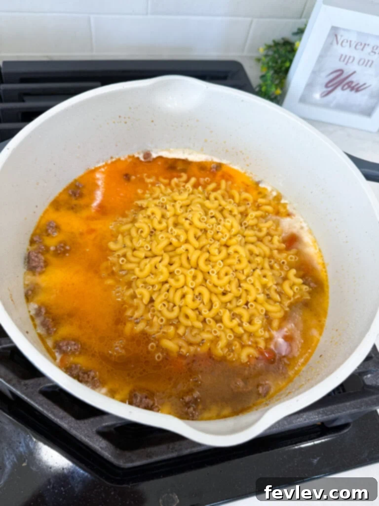 Taco pasta ingredients simmering in a pot on the stovetop, just before the cheese is added.