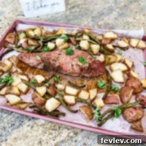 Delicious Roasted Garlic and Black Pepper Pork Tenderloin served on a sheet pan with roasted red potatoes and green beans.