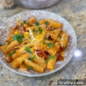 A vibrant bowl of one-pot taco pasta with colorful bell peppers, corn, and cheese, garnished with fresh cilantro, ready to be served.