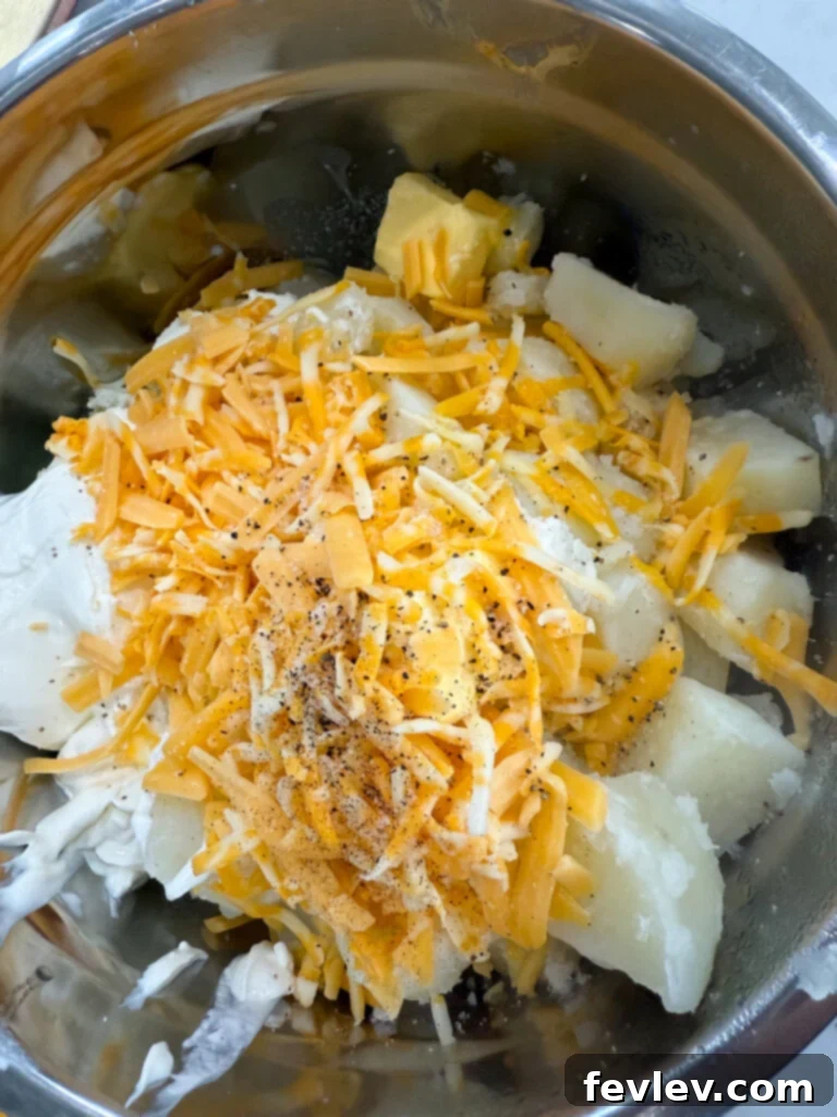 Double Delicious Potato Bake 4 Adding boiled potatoes, butter, sour cream, cream cheese, green onions, bacon, cheese, milk, salt, pepper, and thyme to a large mixing bowl
