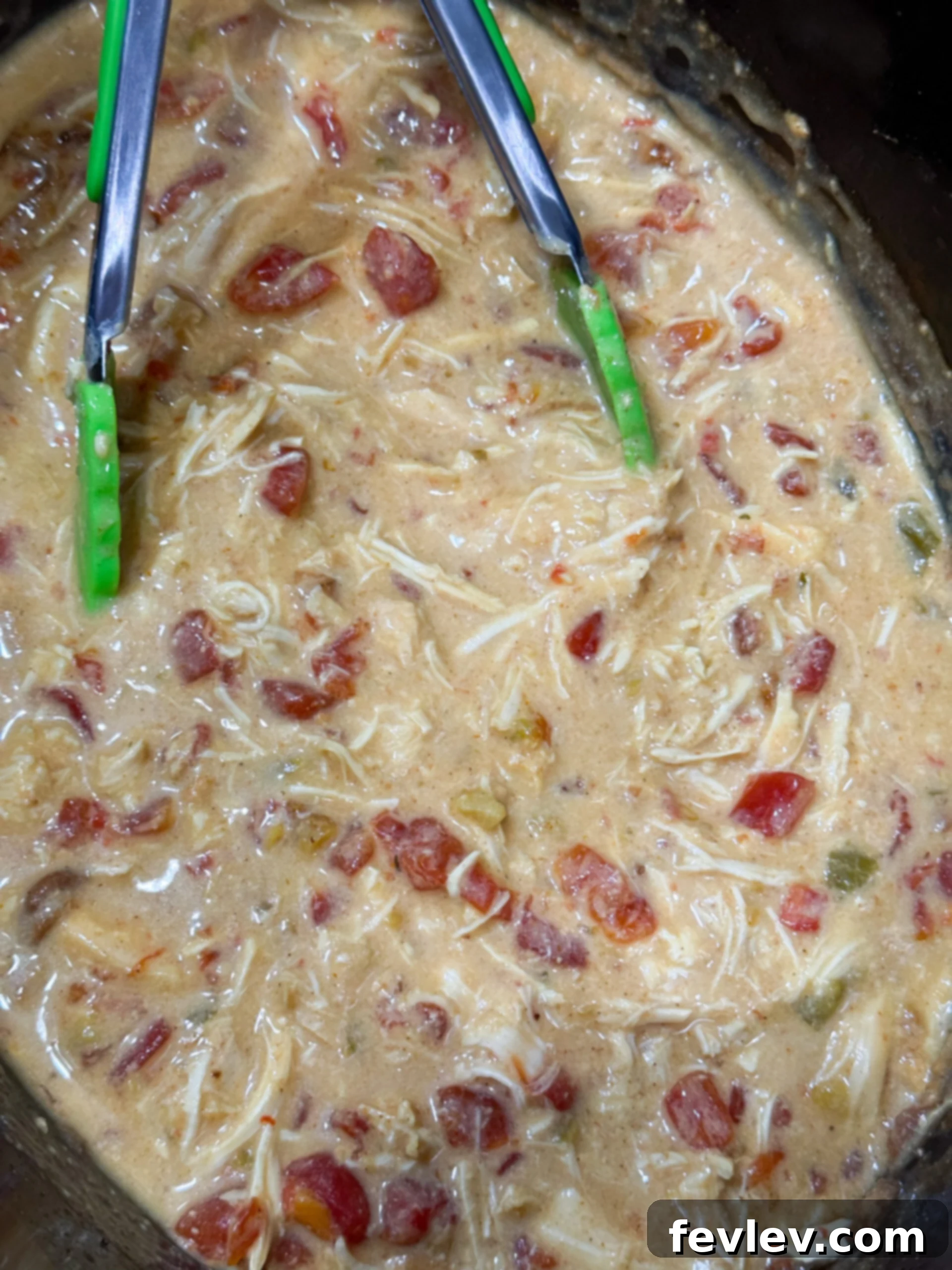 Shredding chicken in creamy queso sauce