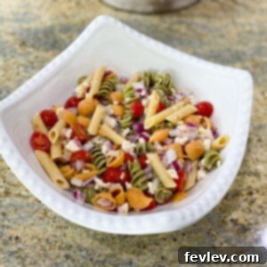 Vibrant and fresh Italian pasta salad with tricolor rotini, cherry tomatoes, cucumbers, red onion, and black olives.