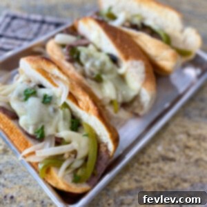 Delicious Sheet Pan Philly Cheesesteak with thinly sliced beef, caramelized onions, and bell peppers on a hoagie roll, topped with melted provolone cheese, ready to be served.
