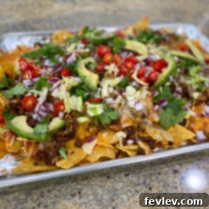 Delicious Sheet Pan Nachos, loaded with melted cheese and fresh toppings