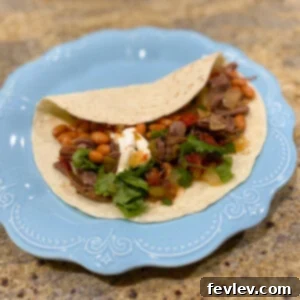 Delicious Slow Cooker Carne Asada with fresh toppings like cilantro and lime