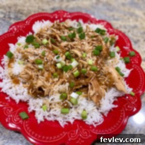 Delicious Slow Cooker Teriyaki Chicken served over rice, garnished with green onions and sesame seeds.