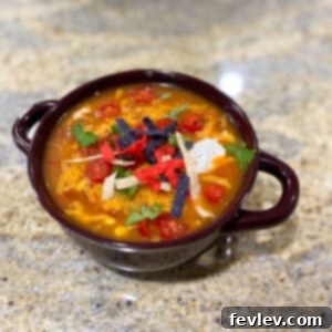 A perfectly portioned bowl of 8 Can Chicken Taco Soup, garnished with a dollop of sour cream, a sprinkle of fresh cilantro, and a vibrant squeeze of lime. The rich, savory broth surrounds tender pieces of chicken, colorful beans, and sweet corn, inviting you to dig in.