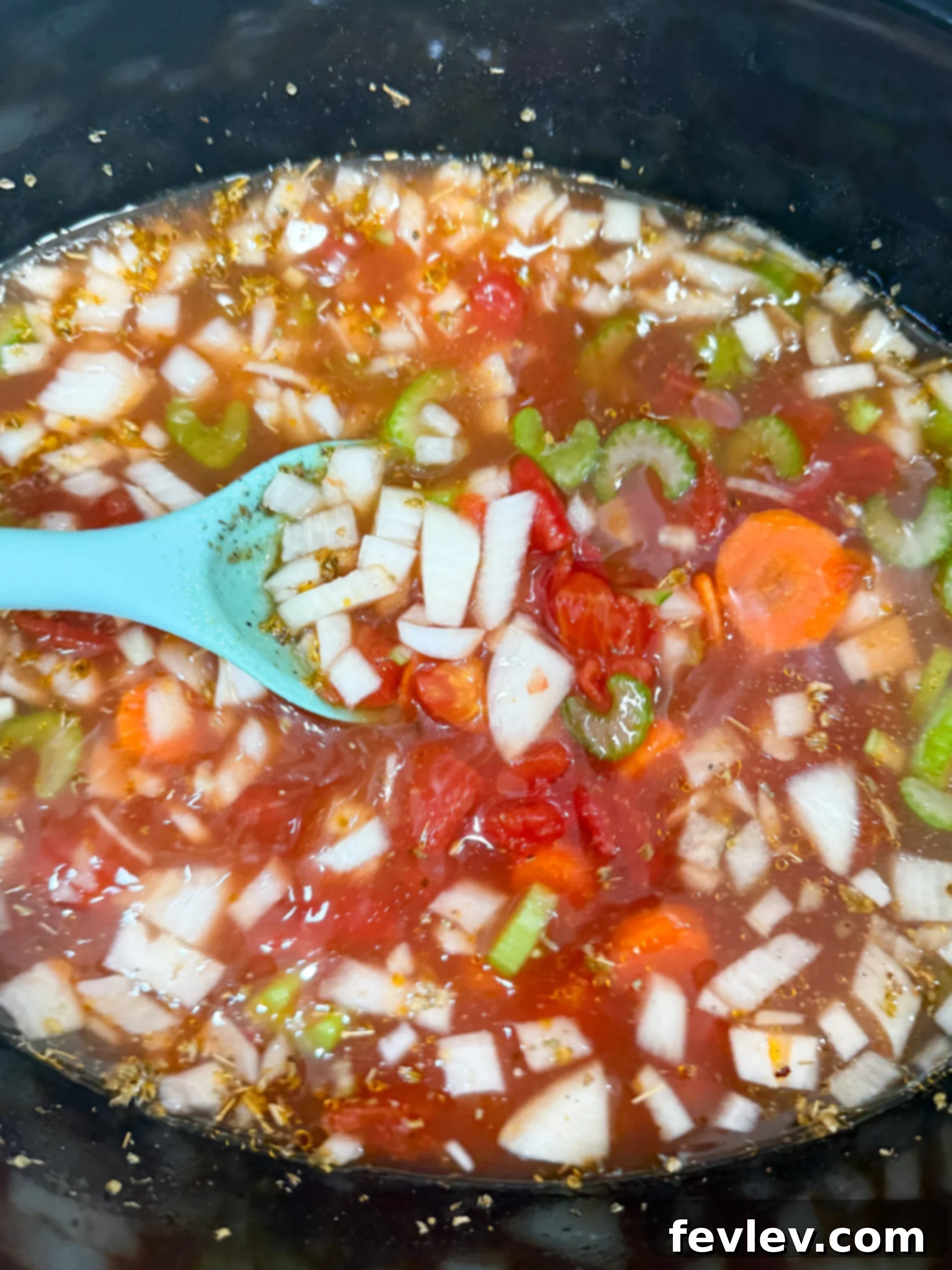 Adding diced tomatoes, tomato paste, sun-dried tomatoes, vegetable broth, carrots, celery, onion, garlic, and seasonings to a large slow cooker.
