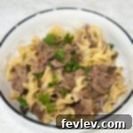 Slow cooker beef stroganoff served with tender noodles and fresh parsley, a rich and creamy comfort meal.