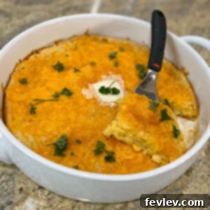 Golden-brown, creamy corn casserole in a round baking dish, garnished with fresh herbs, ready to be served at a family gathering or holiday meal.